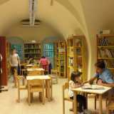 L'ampio ambiente interno della biblioteca: sulla destra una bambina sfoglia un libro accanto al pap�